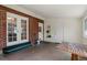 Enclosed porch with exposed brick, white trim and doors leading to the back yard with concrete floor at 160 Northglenn Dr, Northglenn, CO 80233