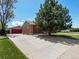 The property features an extended driveway leading to a detached garage with a red door at 160 Northglenn Dr, Northglenn, CO 80233
