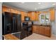Cozy kitchen featuring oak cabinets, black appliances, and granite countertops with tile backsplash at 160 Northglenn Dr, Northglenn, CO 80233