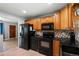 Cozy kitchen featuring oak cabinets, black appliances, and granite countertops with tile backsplash at 160 Northglenn Dr, Northglenn, CO 80233