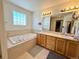 Bathroom featuring a soaking tub, double sinks, and ample counter space at 395 Longspur Dr, Brighton, CO 80601