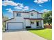 This two-story home includes an attached two-car garage and a well-kept lawn at 395 Longspur Dr, Brighton, CO 80601