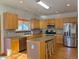 Kitchen featuring an island with stools, stainless steel appliances, and wooden cabinets at 395 Longspur Dr, Brighton, CO 80601
