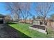 Well-maintained backyard with green grass, mature trees, garden and wooden fence at 5775 S Pagosa Way, Centennial, CO 80015