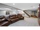 Finished basement with a large leather sectional, projector, and stairs leading to the upper level at 5775 S Pagosa Way, Centennial, CO 80015