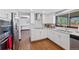 Updated kitchen with stainless steel appliances, white cabinetry, marble countertops, and hardwood floors is ready for cooking at 5775 S Pagosa Way, Centennial, CO 80015