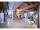 Unfinished basement featuring exposed plumbing, stairs, and a white refrigerator at 530 S Laredo Cir, Aurora, CO 80017