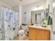 Bathroom featuring light tile flooring, a vanity sink, a mirror, and a shower with a decorative leaf curtain at 726 Vista Verde Hts, Monument, CO 80132