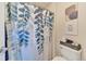 A clean bathroom with a blue-themed shower curtain featuring leaves, a toilet, and a white basket for storage at 726 Vista Verde Hts, Monument, CO 80132