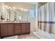 Bathroom featuring a double vanity with granite countertops, decorative mirror, and a bathtub at 10057 Granby St, Commerce City, CO 80022