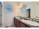 Well-lit bathroom featuring double sinks with dark wood cabinets and mosaic backsplash at 10057 Granby St, Commerce City, CO 80022