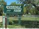 A covenant controlled community entrance sign that reads 'Riverdale Farm' with a green field visible in the background at 8480 Adams Way, Denver, CO 80229