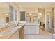 Bright bathroom featuring dual sinks, tile floors, makeup area, and glass-enclosed shower at 16 Blue Heron Dr, Thornton, CO 80241