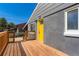 View of the front of the home with a grey exterior, a yellow front door, and a wood porch at 695 S Quitman St, Denver, CO 80219