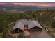 Expansive aerial view of a stunning mountain home with mature trees and scenic views at 26452 Wolverine Trl, Evergreen, CO 80439