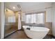 Modern bathroom featuring a soaking tub, glass shower, and a large window that provides natural light at 26452 Wolverine Trl, Evergreen, CO 80439