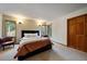 Cozy bedroom with two leather chairs, a bed with decorative pillows, and scenic views from two windows at 26452 Wolverine Trl, Evergreen, CO 80439