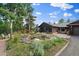 Landscaped yard featuring a tranquil pond, lush greenery, and a home with a covered outdoor space at 26452 Wolverine Trl, Evergreen, CO 80439