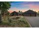 Charming home exterior with lush landscaping, a serene pond, and a two-car garage, bathed in the warm glow of dusk at 26452 Wolverine Trl, Evergreen, CO 80439
