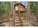 Cozy cabin featuring a small porch and wooden stairs, surrounded by a peaceful wooded setting at 26452 Wolverine Trl, Evergreen, CO 80439