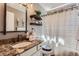Bathroom featuring a granite vanity, decorative mirror and shelves, and shower with a patterned shower curtain at 10330 Lions Path, Lone Tree, CO 80124