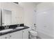 Bright bathroom featuring double sink vanity with black countertop and white tiled shower and tub at 3529 Xanthia Ct, Denver, CO 80238