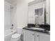 Bright bathroom featuring single sink vanity with black countertop and white tiled shower and tub at 3529 Xanthia Ct, Denver, CO 80238