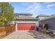 Attached garage with a red door, spacious driveway, and solar panels on the house at 3529 Xanthia Ct, Denver, CO 80238