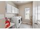 Bright laundry room with modern washer and dryer, storage cabinets, and a window for natural light at 3529 Xanthia Ct, Denver, CO 80238