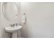 Small powder room featuring a pedestal sink and round mirror at 3529 Xanthia Ct, Denver, CO 80238
