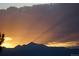 Dramatic sunset with a silhouette of a mountain range and sun rays shining through the clouds at 4939 Silver Feather Cir, Broomfield, CO 80023