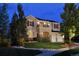 Beautiful home at dusk with illuminated landscaping, stone accents, and a welcoming two-car garage at 4939 Silver Feather Cir, Broomfield, CO 80023