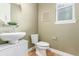 A half bathroom featuring white vanity, wood look floor, and decorative mirror at 676 Fossil Bed Cir, Erie, CO 80516