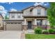 Charming two-story home featuring a manicured lawn and a welcoming front porch with stone accents at 676 Fossil Bed Cir, Erie, CO 80516