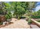 A backyard stone patio surrounded by mature trees and professional landscaping provides beauty and privacy at 1473 E 130Th Dr, Thornton, CO 80241