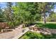 Backyard stone patio featuring professional landscaping and mature trees providing shade and privacy at 1473 E 130Th Dr, Thornton, CO 80241