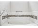 Close-up of a bright white soaking tub with mosaic tile backsplash and chrome fixtures at 56582 E 23Rd Ave, Strasburg, CO 80136