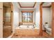 Spa-like bathroom with soaking tub, walk-in shower, wood trim, and serene window view at 9650 S Cougar Rd, Littleton, CO 80127