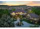 Stunning exterior elevation of grand home, with manicured front yard and mountain views at sunset at 9650 S Cougar Rd, Littleton, CO 80127