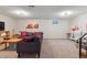 Spacious basement with plush seating area, decorative wall art, and functional workspace with adjacent stairs at 11402 W 17Th Pl, Lakewood, CO 80215