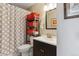 Well-lit bathroom features modern sink with storage, a toilet, and a decorative patterned shower curtain at 11402 W 17Th Pl, Lakewood, CO 80215