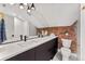 Modern bathroom with white subway tiles, brick accent wall, and double vanity at 1730 N Gaylord St, Denver, CO 80206