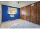 Bedroom featuring wood paneled and blue walls, with a window and damaged walls and floors at 4291 W Wagon Trail Dr, Littleton, CO 80123