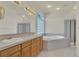 Bright bathroom featuring a soaking tub, dual sinks, and glass-enclosed shower, offering a spa-like experience at 11017 Meade Ct, Westminster, CO 80031