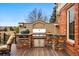 Close-up of an outdoor kitchen featuring a stone facade and stainless steel grill, seamlessly integrated into the outdoor setting at 7086 Esperanza Dr, Castle Pines, CO 80108