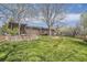 Expansive backyard features mature trees, lush green grass, patio and a stone retaining wall at 5876 W Canyon Ave, Littleton, CO 80128