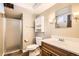 Neutral bathroom features a shower, toilet, sink with wood vanity and functional wall storage at 5876 W Canyon Ave, Littleton, CO 80128