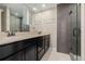 Modern bathroom showcasing a double vanity, a stylish mirror, and a glass-enclosed shower at 8231 E Lehigh Dr, Denver, CO 80237