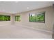 This carpeted bedroom has neutral walls and large windows overlooking a green landscape at 8231 E Lehigh Dr, Denver, CO 80237