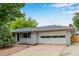 Well-maintained single-story home, painted gray, with a large two car garage and mature landscaping at 8231 E Lehigh Dr, Denver, CO 80237